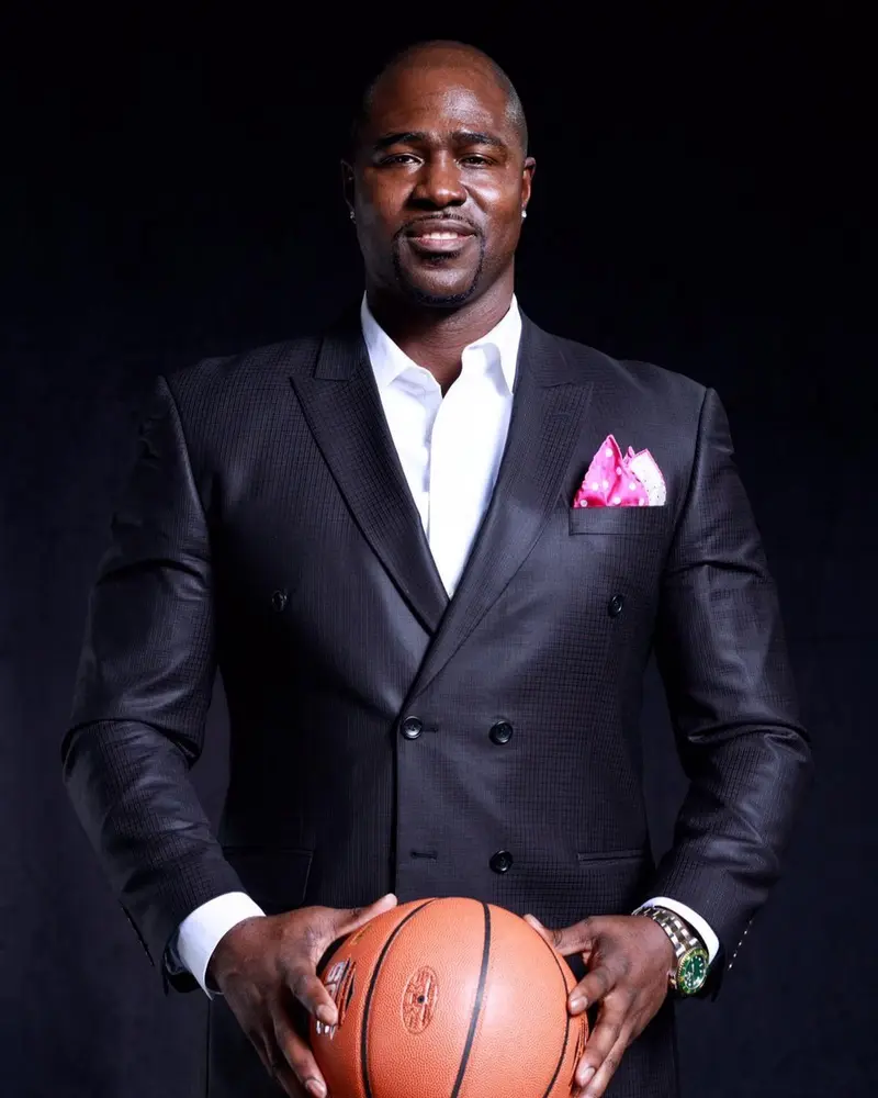 Portrait of Gary Durrant in a black suit, holding a basketball